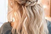 a boho wedding half updo with a messy voluminous top, a double braided halo and waves down plus bangs