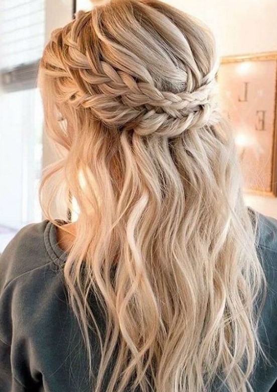 a boho wedding half updo with a messy voluminous top, a double braided halo and waves down plus bangs