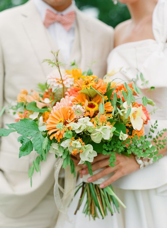 a bold orange wedding bouquet with orange, coral and white blooms and textural greenery is amazing