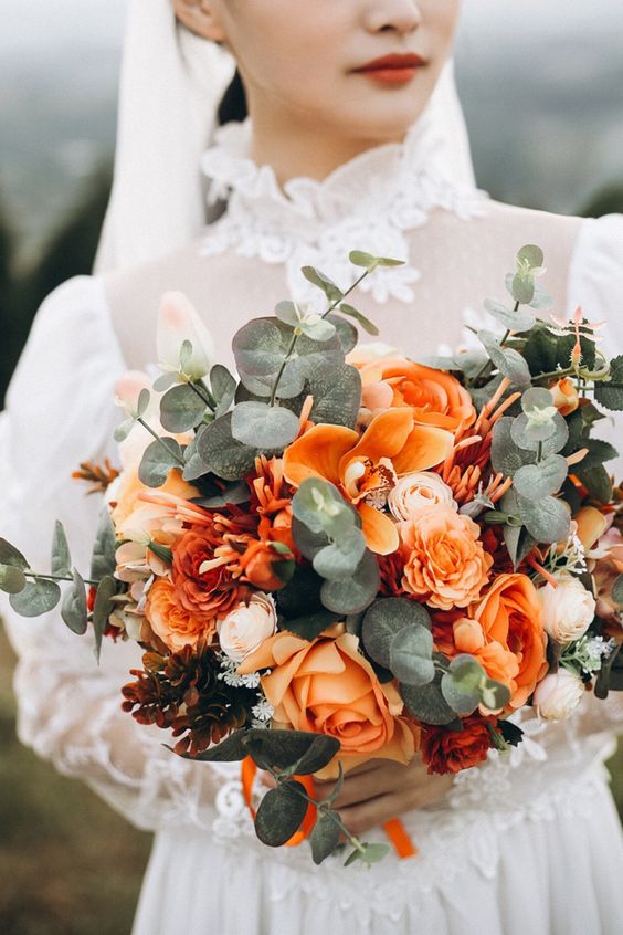 a bright orange wedding bouquet of eucalyptus, orange roses and orchids, dark flowers is amazing for summer or fall
