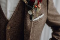 a chic brown tweed three-piece suit, a whiet shirt, a burgundy velvet bow tie and a floral boutonniere