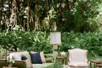 a chic vintage outdoor wedding lounge with a green sofa and neutral chairs, a range of vintage coffee tables and a printed rug