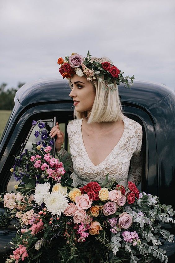 a colorful floral crown with lilac, red and orange and blush blooms and some greenery for a spring or summer boho wedding