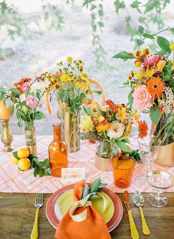 a colorful summer wedding tablescape with a bold printed runner, bold pink, orange and yellow blooms and greenery and colorful plates