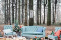 a colorful woodland wedding lounge with blue seating furniture, coral pillows, a coffee table, bold blooms and greenery