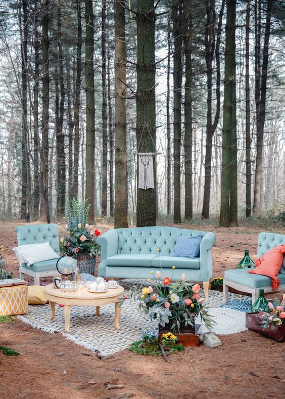 a colorful woodland wedding lounge with blue seating furniture, coral pillows, a coffee table, bold blooms and greenery