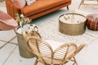 a cool boho outdoor wedding lounge with a rust-colored sofa, neutral and a pink chair, pink and Moroccan pillows, metal hammered tables, bright blooms