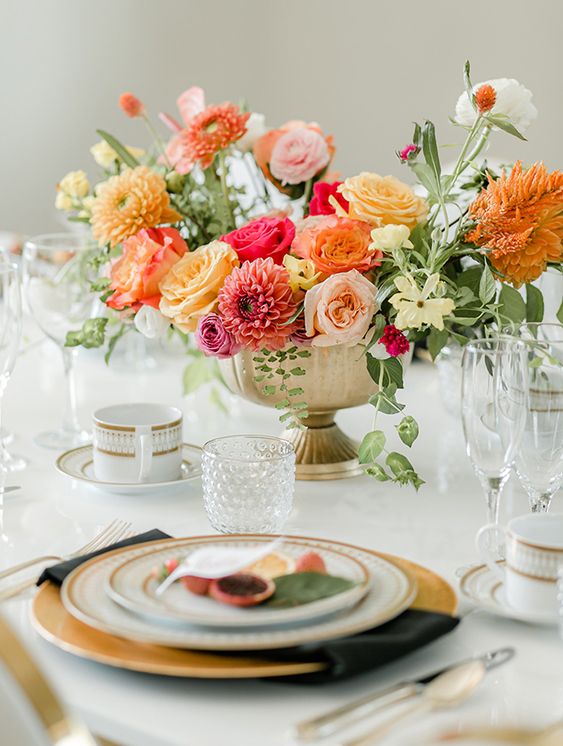 a fantastic summer wedding centerpiece of white, blush, yellow, orange and pink blooms and greenery is vivacious