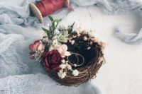 a faux bird nest decorated with fresh blooms and greenery is a very cozy and cute idea for a woodland or backyard wedding