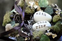 a faux bird nest with moss, foliage and berries plus fake eggs with letters for a fall or spring woodland wedding