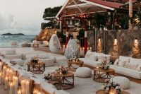 a gorgeous neutral beach lounge with pastel and neutral blooms, egg-shaped chairs, neutral sofas and pillar candles, wooden tables