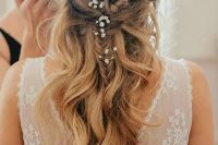a half updo with a braid and waves down and some baby’s breath tucked into the hair for a super romantic and delicate beach bridal look
