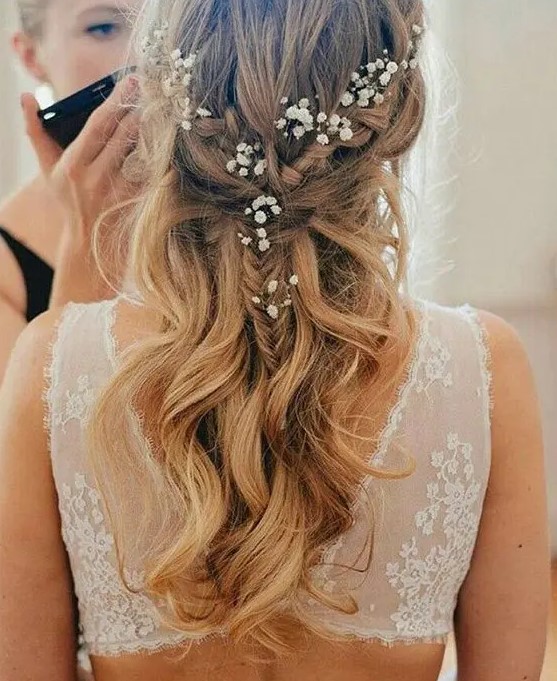 a half updo with a braid and waves down and some baby's breath tucked into the hair for a super romantic and delicate beach bridal look