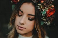 a large floral crown with burgundy and red blooms, lotus and greenery for a fall boho bride
