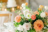 a lovely neutral wedding tablescape with orange and white blooms and greenery, candles is a lovely idea for a summer wedding