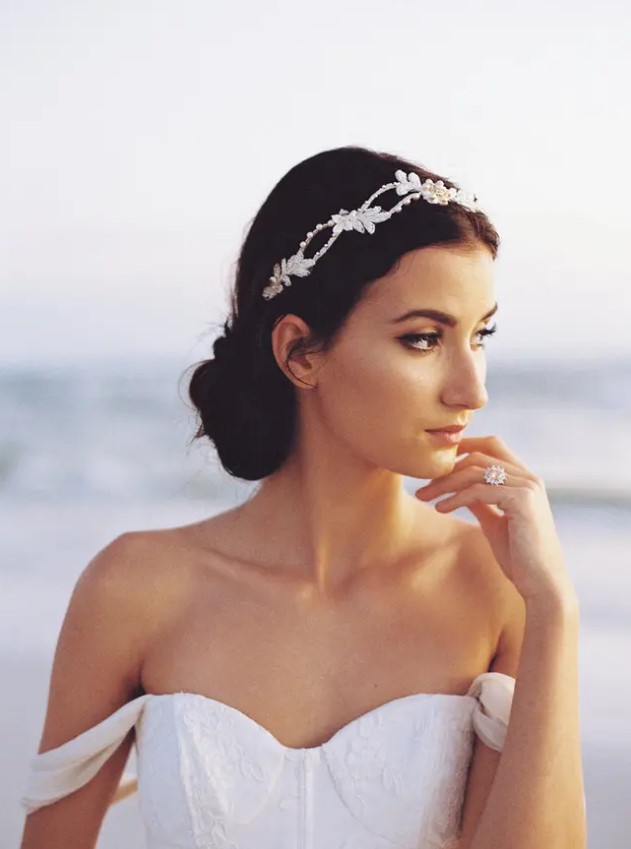 a low braided bun with a gorgeous sparkling headpiece with pearls and rhinestones for a refined and chic bride