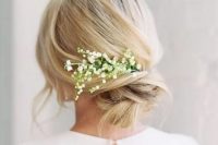 a messy twisted chignon with some bangs and lily of the valley tucked in is a romantic idea for a spring bride, at a beach or some other wedding