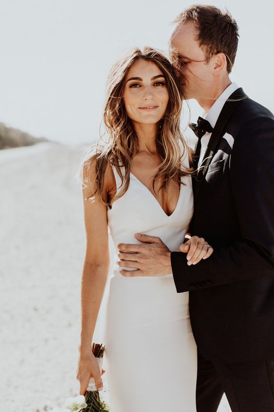 a minimalist sheath wedding dress with a deep neckline and a train is a cool option to wear right now