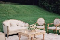 a neutral vintage wedding lounge with refined and chic furniture, a printed rug, a low coffee table and some neutral blooms