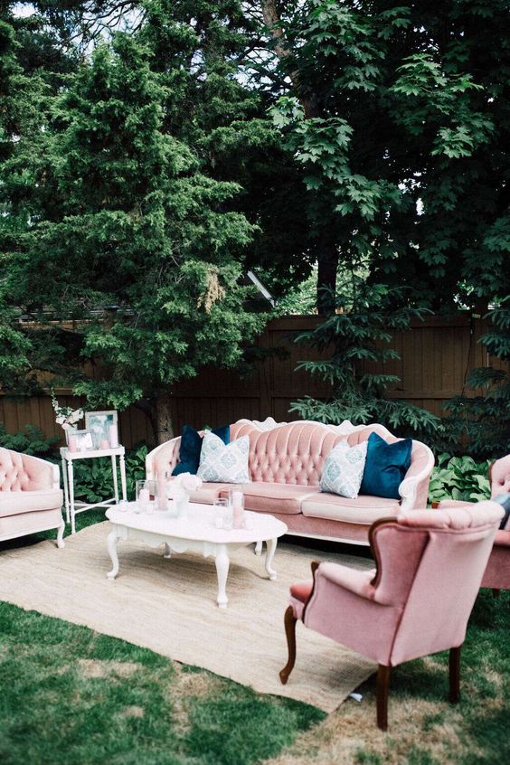 a pink vintage lounge with refined furniture, blue pillows, coffee tables and a neutral rug will fit a summer wedding