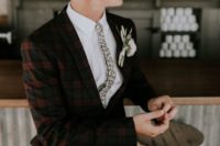 a quirky retro look with a red and black checked suit, a white shirt and a floral tie plus a florla boutonniere