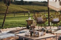 a relaxed outdoor boho wedding lounge with a low coffee table, lots of layered rugs, poufs and pillows, rattan chairs and tassels