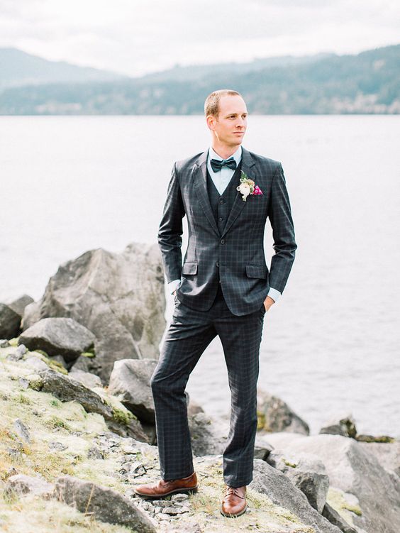 a retro groom's look with a navy windowpane print suit in three pieces, an aqua shirt, a blue bow tie and brown shoes