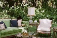 a sophisticated garden wedding lounge with a green sofa, a neutral chair, a glass coffee table, a printed rug and some bold pillows