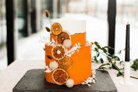 a stunning white and orange wedding cake with white dried grasses and dried citrus slices is a lovely idea for a tropical boho wedding
