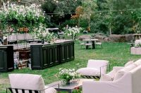 a stylish black and white outdoor wedding lounge with a white sofa, black and white chairs, black coffee tables and white blooms