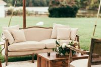 a stylish neutral vintage wedding lounge with a sofa, some chairs, a stained chest for storage and some neutral blooms