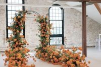 a super bold indoor wedding arch decorated with greenery and lots of orange blooms looks amazing