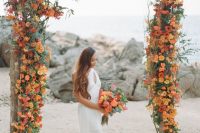 a super bold wedding arch covered with orange, red and rust blooms and lots of greenery is a gorgeous idea for a summer or fall wedding arch