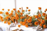 a super lush wedding tablescape with bold orange flowers, orange candles and white linens is a great idea for summer or fall