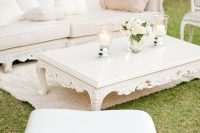 a super refined neutral wedding lounge with exquisite carved furniture, a low coffee table, white blooms and pillar candles