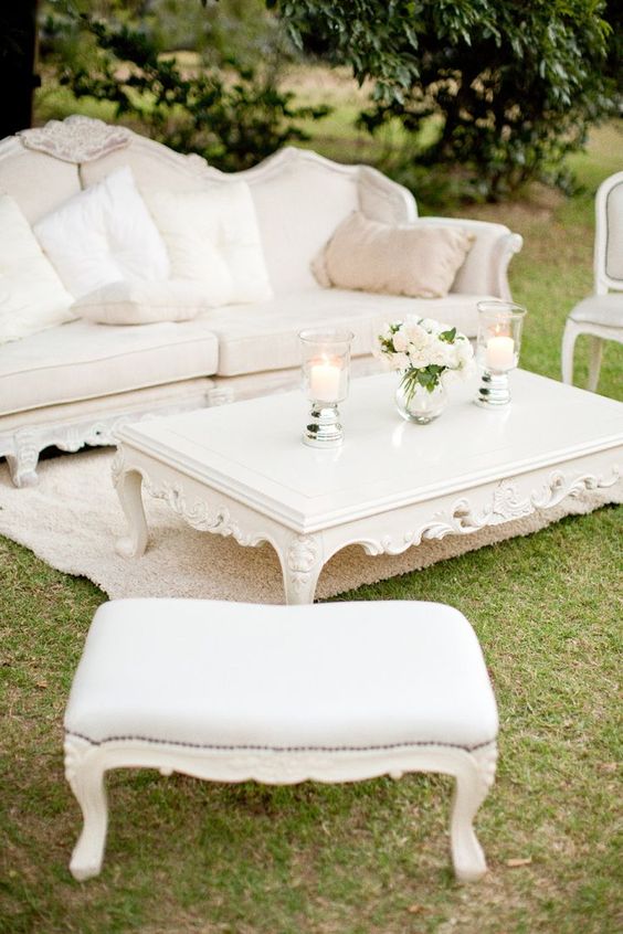 a super refined neutral wedding lounge with exquisite carved furniture, a low coffee table, white blooms and pillar candles