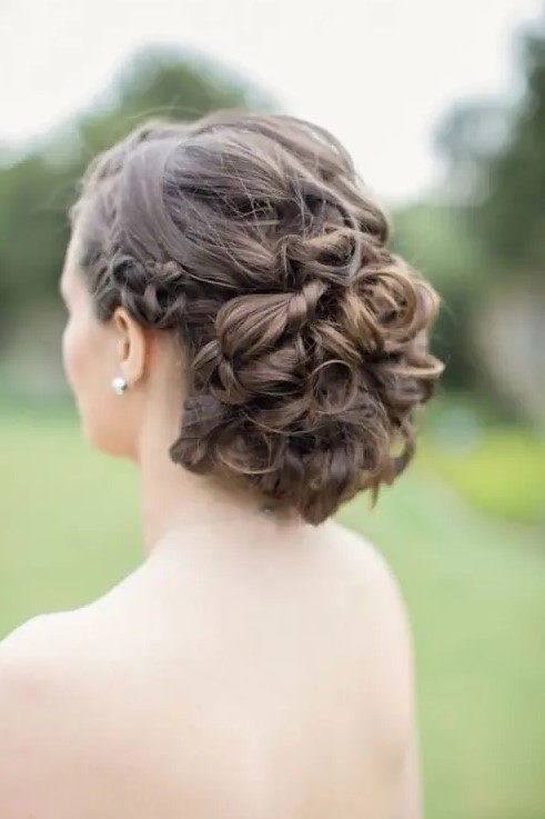 a twisted and curly wedding updo with a complicated and layered top and a braided halo for brides with long and extra long hair