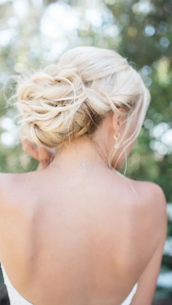 a twisted low bun with some locks down, with locks framing the face is a gorgeous idea  for a chic and elegant look not only at a beach wedding