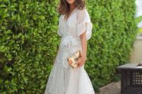 a white midi dress with sheer details, wide sleeves and an asymmetrical skirt plus black heels