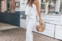 a white strapless jumpsuit with a tiered bodice, statement earrings and a wooden bag