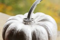 a whitewashed pumpkin with wedding rings on the stem is a fun idea for a fall wedding