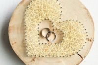 a wood slice with nail and yarn hearts is a trendy and bold idea for a woodland or rustic wedding