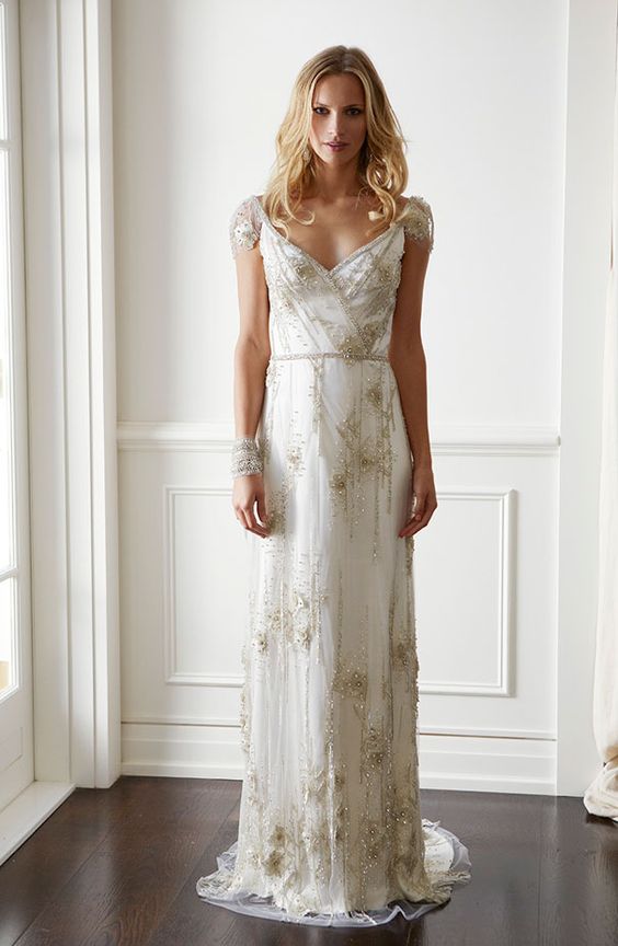 a 1920s embellished neutral wedding dress with gold embellishments and embroidery plus a train, a deep V-neckline and cap sleeves