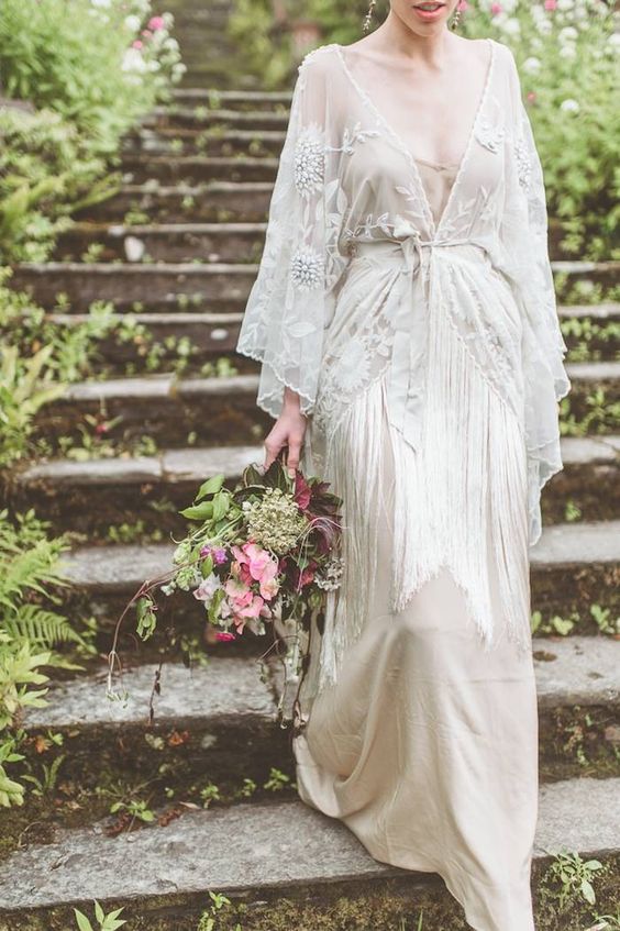a 1920s inspired embellished wedding dress with a sash, long fringe and tan underdress plus wide embellished sleeves