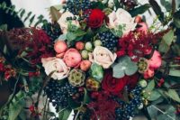 a beautiful dimensional fall wedding bouquet with berries, greenery, blush and pink blooms and touches of deep red