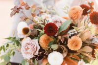 a beautiful fall wedding bouquet of white, pink, burgundy, orange blooms, greenery and dark foliage with much dimension is amazing