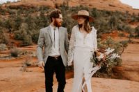 a boho lace fitting wedding gown with long sleeves and a front slirt plus a small train and a hat for a boho elopement