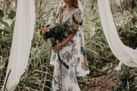 a boho white wedding dress all covered with blue embroidery and tassels for a boho elopement