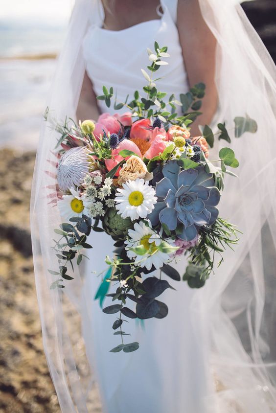 a bold and catchy wedding bouquet of white and coral blooms, a king protea, a succulent and eucalyptus is a fantastic idea