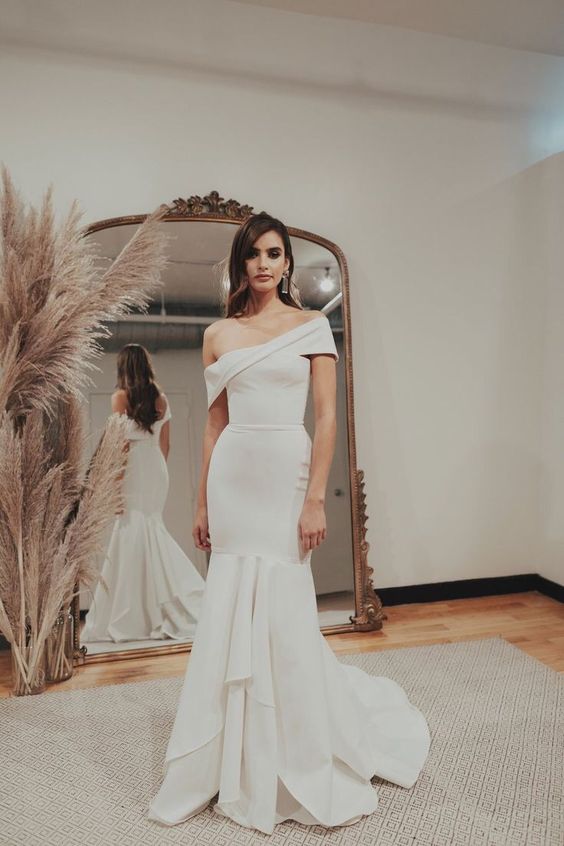 a bold and unusual one shoulder mermaid wedding dress with a layered skirt and a train is a fantastic solution to catch an eye